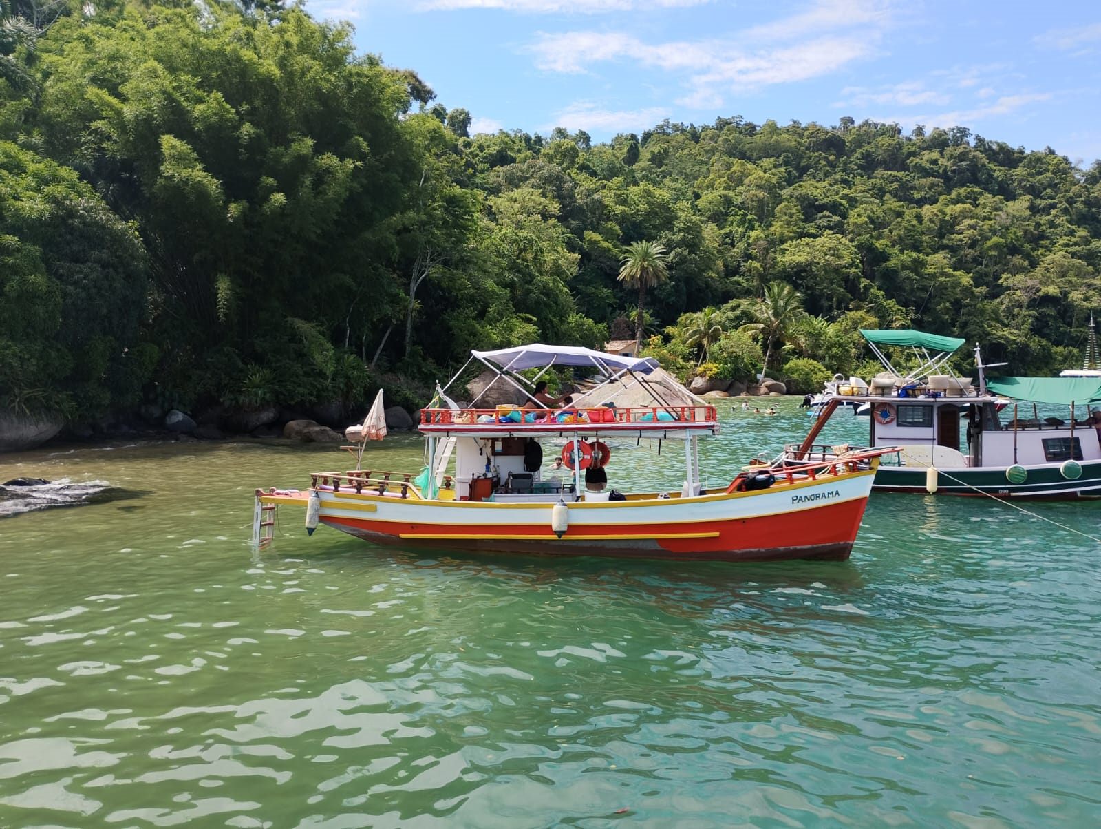 Barco Panorama em enseada protegida com pedras e vegetacao