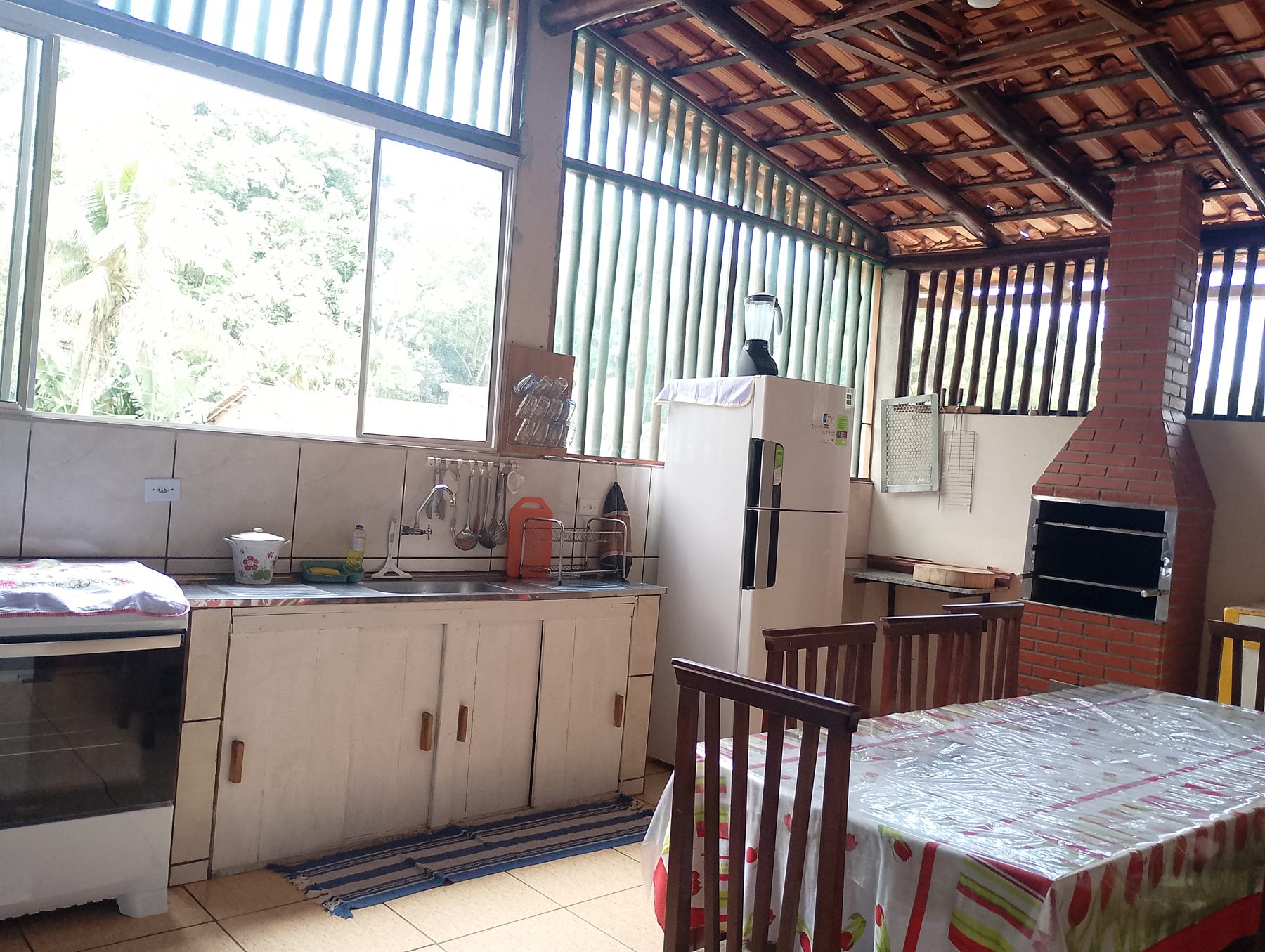 Cozinha ampla da Casa Toa Toa com churrasqueira de tijolos